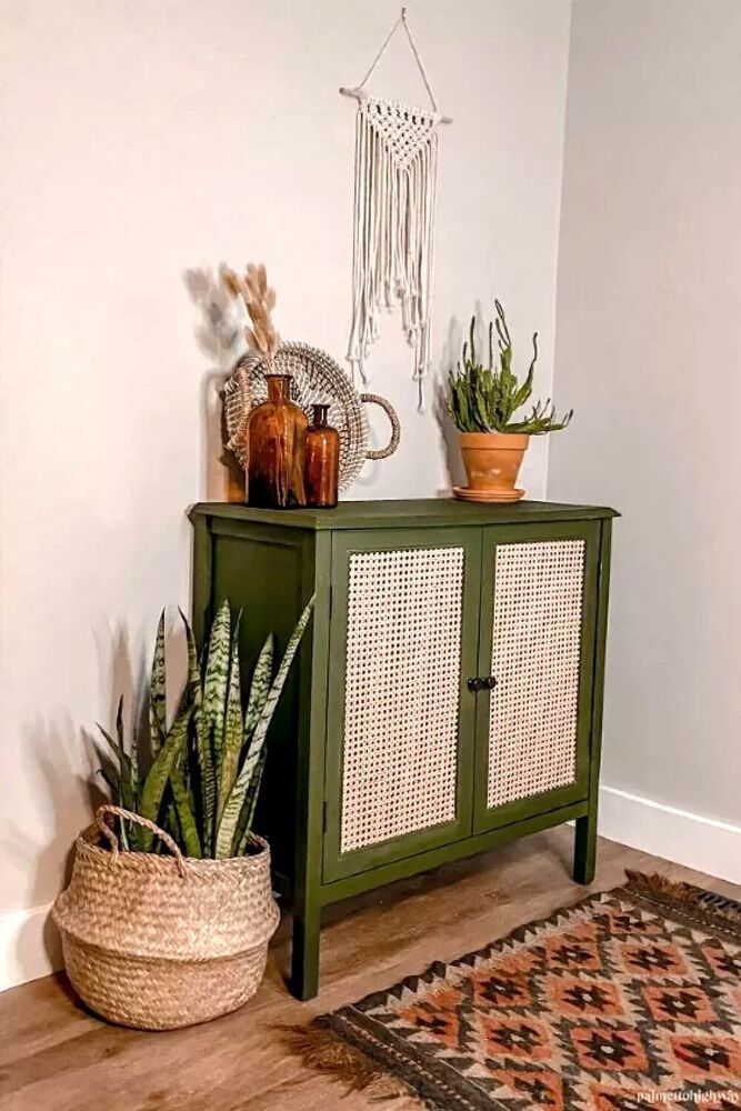 a green cabinet sitting on top of a wooden floor next to a potted plant