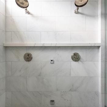 a white tiled bathroom with two shower heads