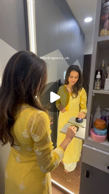 a woman standing in front of a mirror looking at herself in the mirror and smiling