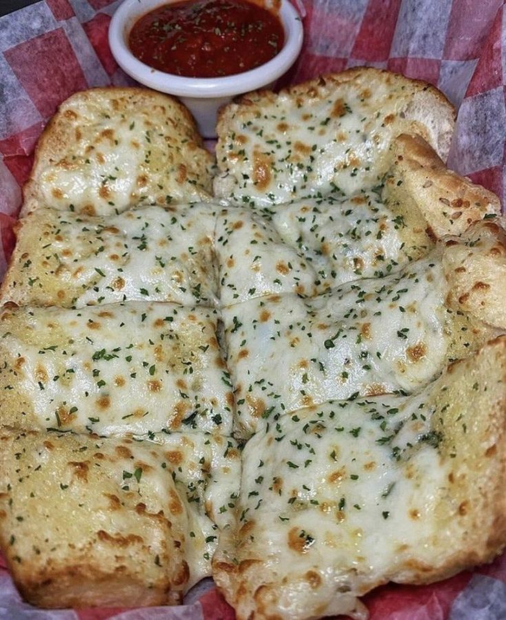 a pizza with cheese and sauce on it sitting on top of a red checkered paper