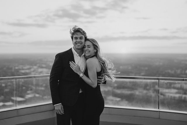 a man and woman standing next to each other on top of a building