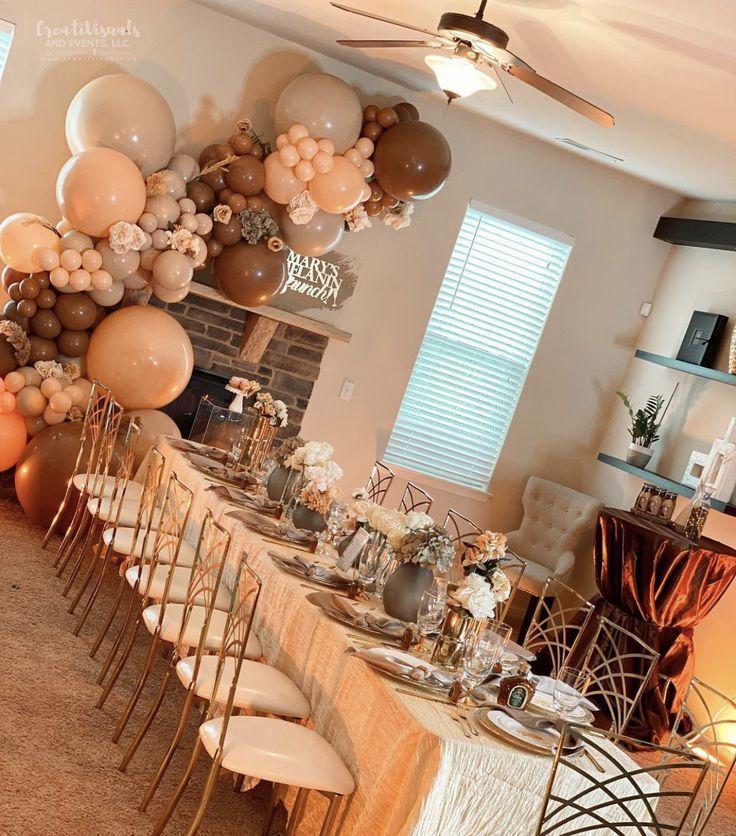 a long table with many balloons on it and chairs in front of the table is set up for a party