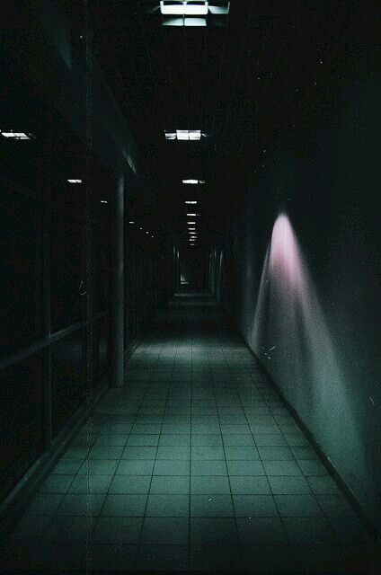 a dark hallway with light coming from the ceiling