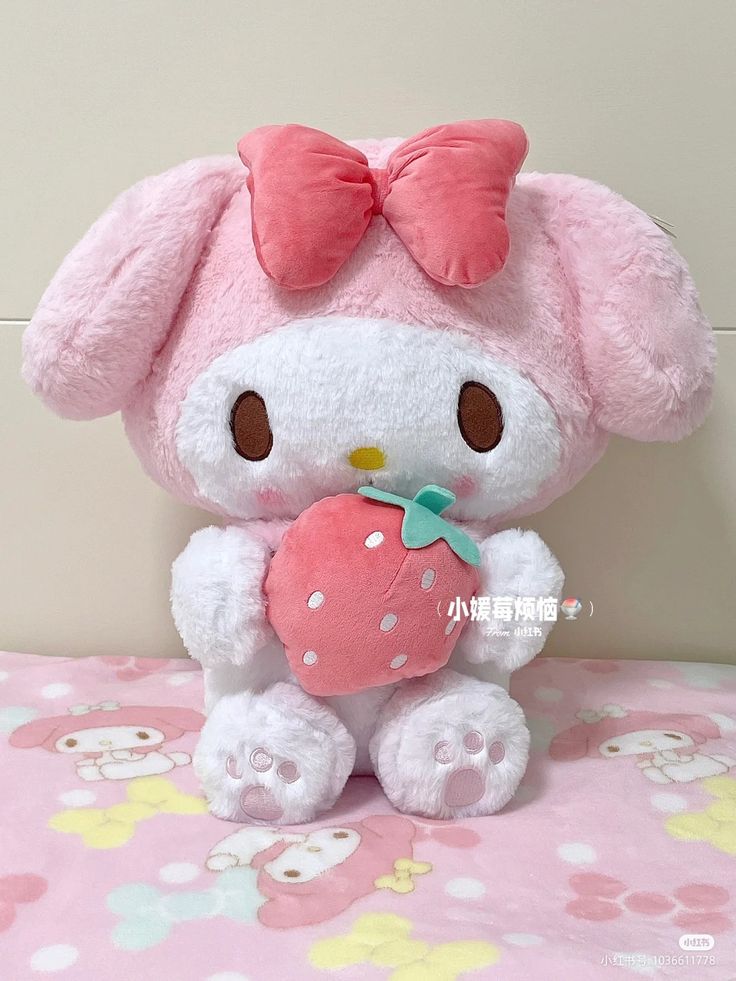 a hello kitty stuffed animal holding a heart on a pink and white floral print tablecloth