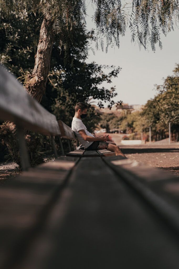 a man sitting on a bench next to a tree