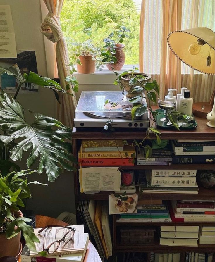 there is a desk with books and plants on it