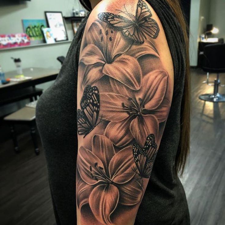 a woman's arm with flowers and butterflies on the back of her shoulder, which is covered in black ink