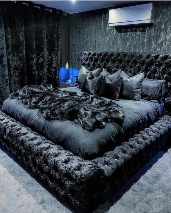 the bed is made up with black fur and pillows on it's headboard