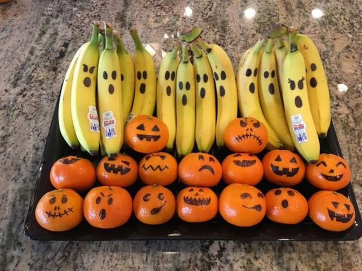 oranges and bananas with faces drawn on them are arranged in a display for halloween