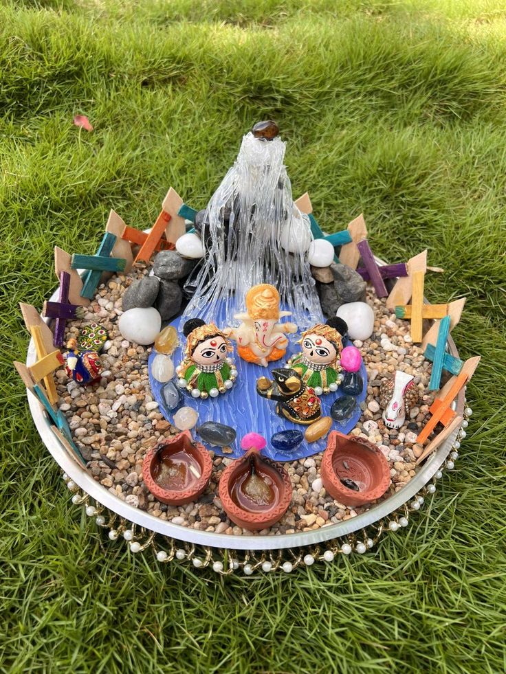 a small garden fountain in the middle of some rocks and gravel with little figurines around it