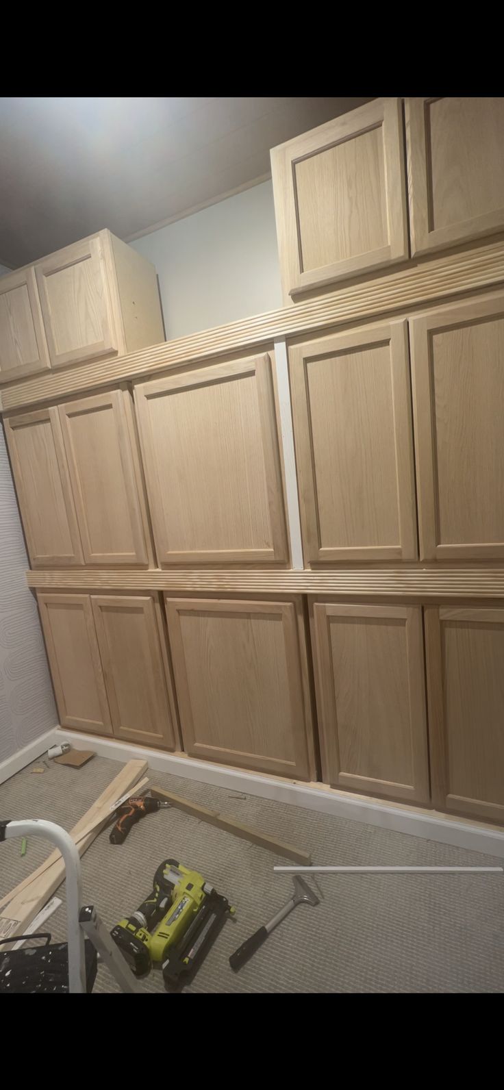 an unfinished kitchen cabinet with tools on the floor in front of it and some cabinets behind it