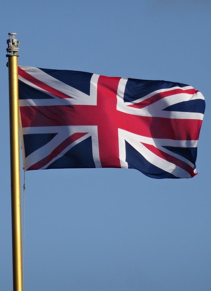 the british flag is flying high in the blue sky with a gold pole on it