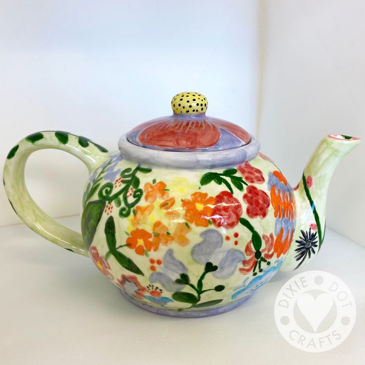 a ceramic teapot with flowers painted on it