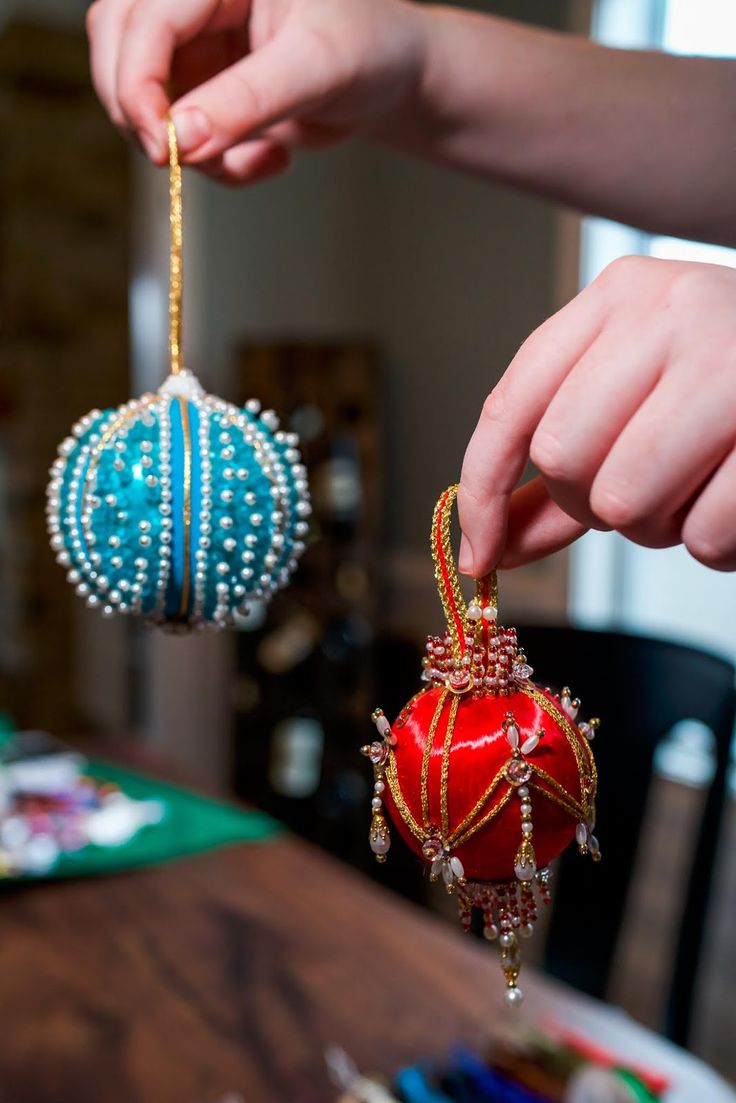 two ornaments are being held by someone's hands on a table with other decorations