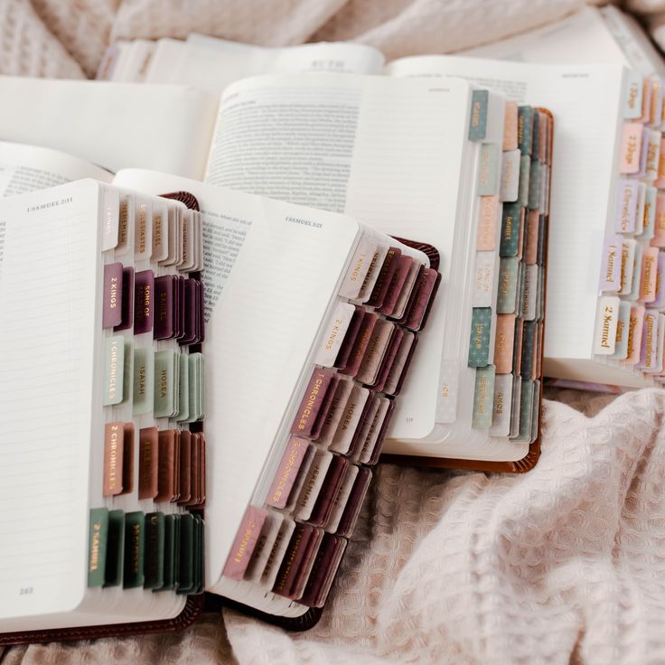 an open book sitting on top of a bed filled with lots of different colored pencils