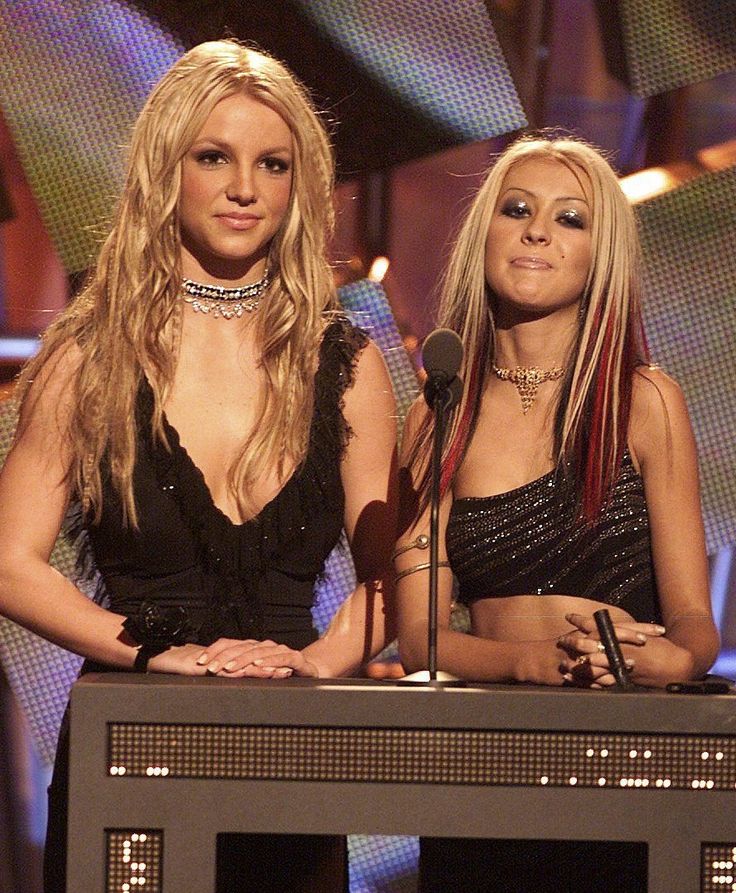 two women standing next to each other at a stage with microphones in front of them