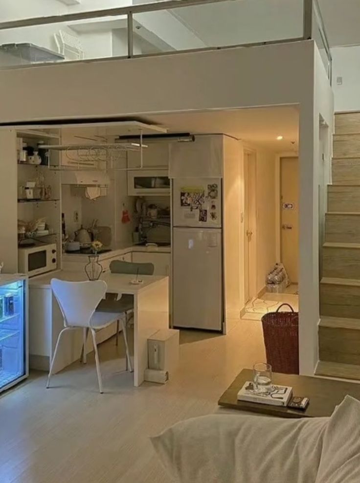 a living room filled with furniture next to a kitchen and dining room table in front of a staircase