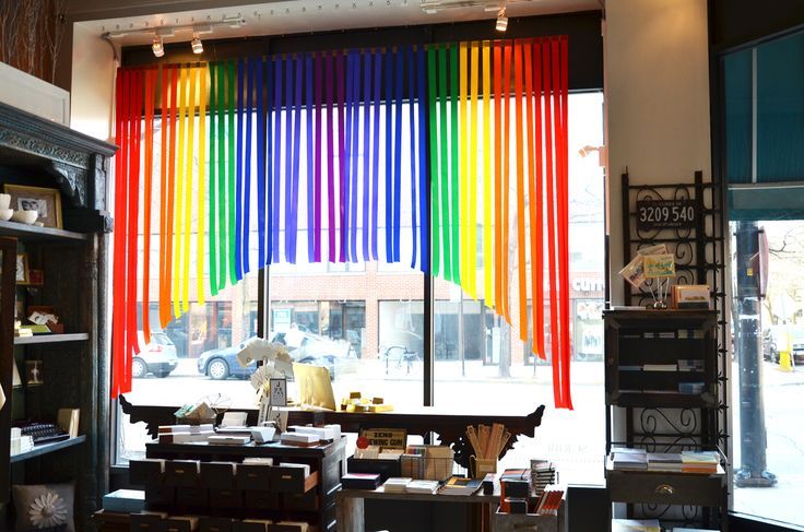 a rainbow colored curtain hangs in front of a window with bookshelves and desks