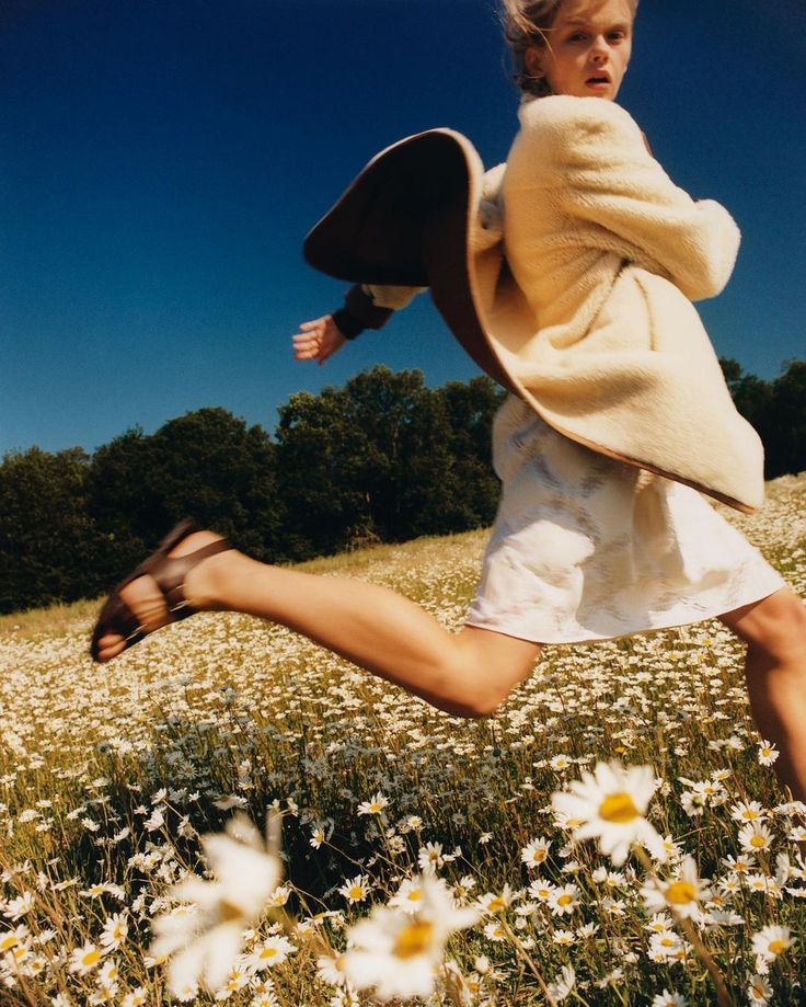 a woman is running through a field full of daisies