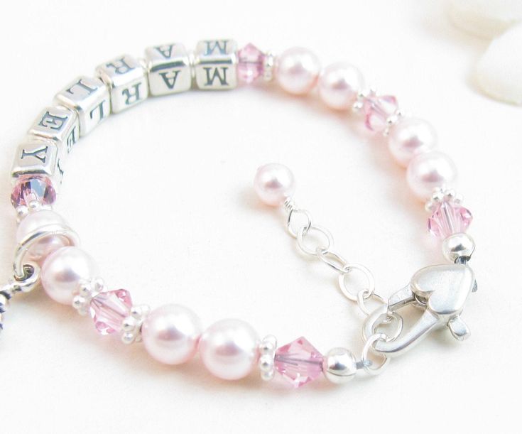 "Pink Beaded Name Bracelet for Child, Infant, Baby, or Little Girl: Created with pink Swarovski pearls and crystals and bright sterling silver spacers. Petite sterling silver alphabet beads spell out her name. The bracelet closes with a high-quality sterling silver heart-shaped lobster clasp with a 1/2\" \"Grow-with-Me\" extender chain. Choose one sterling silver charm. All metal components are sterling silver. Arrives packaged in my signature high-quality reusable canvas gift bag. Beautiful and Pink Beaded Bracelets With Name, Pink Beaded Bracelet With Name, Pink Birthstone Jewelry For Birthday, Hypoallergenic Pink Jewelry For Birthday, Pink Personalized Jewelry For Anniversary, Pink Jewelry With Name For Anniversary, Pink Beaded Bracelets For Birthday, Pink Birthstone Jewelry For Birthdays, Pink Name Bracelet