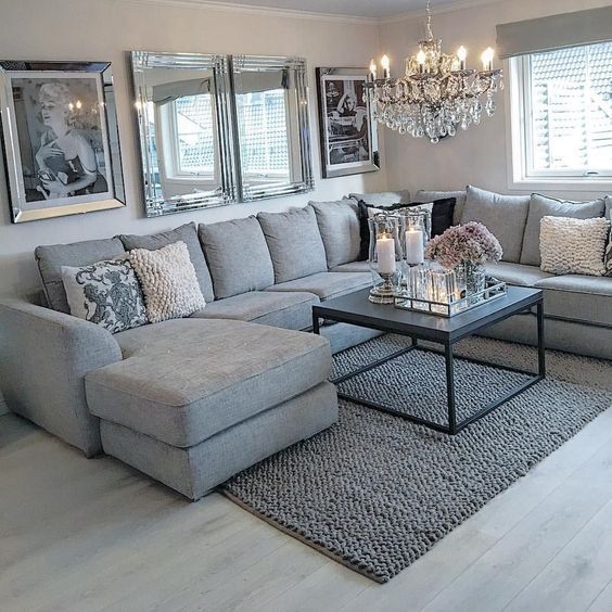 a living room filled with lots of furniture next to a chandelier hanging from the ceiling