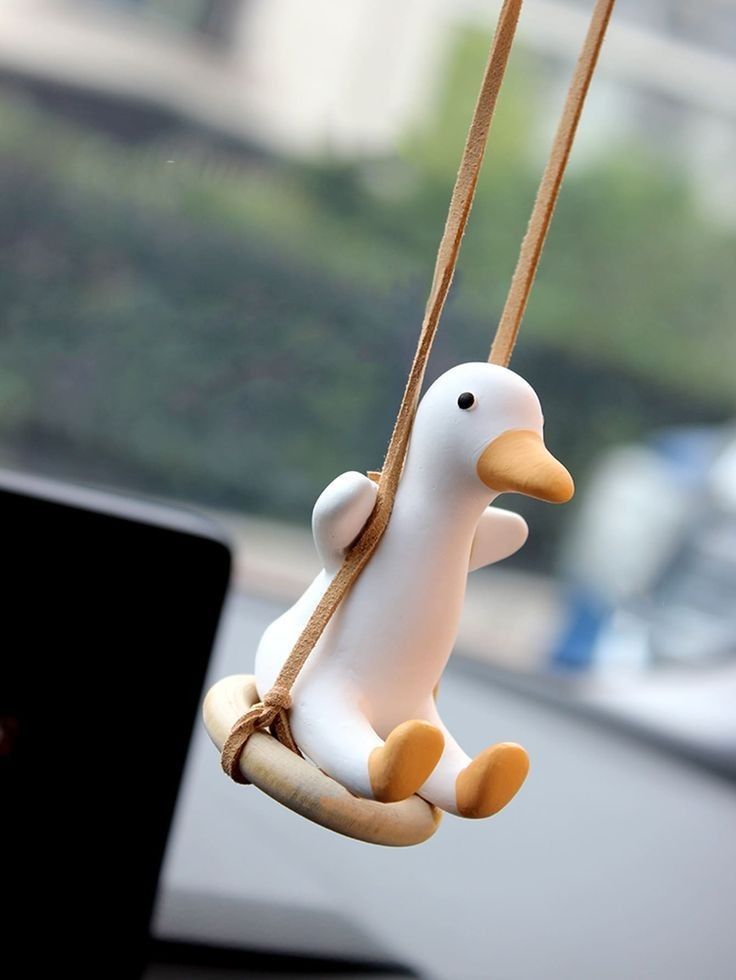 a toy duck is hanging from a rope on a car dashboard with a laptop in the background