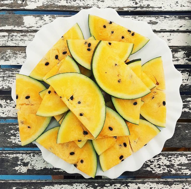 a white plate topped with slices of watermelon on top of a wooden table