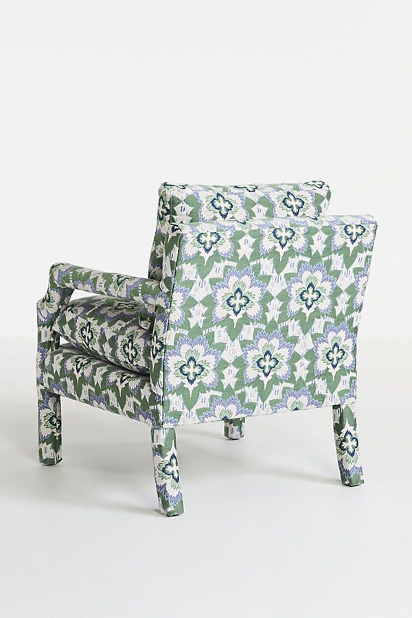 a green and blue patterned chair sitting on top of a white floor