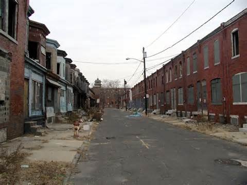 an empty street lined with brick buildings and broken down fire hydrant in the foreground