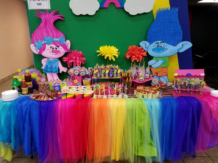 the table is covered with colorful candy and decorations, including trolly faces on them