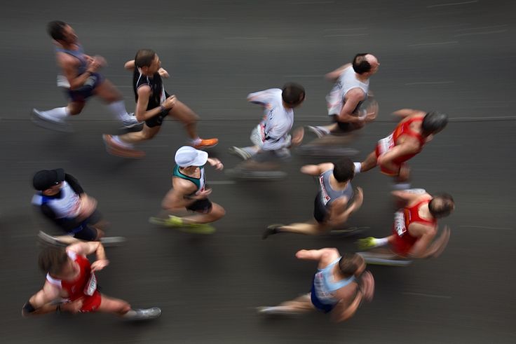 a group of people running down a street next to each other