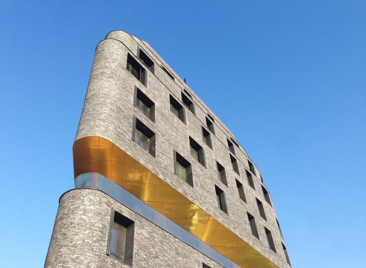 a tall brick building with windows and gold trim on it's side against a blue sky