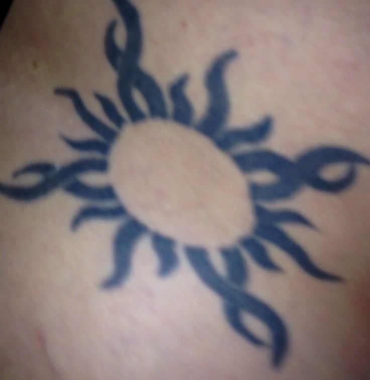 a sun tattoo on the back of a woman's upper body, with black ink