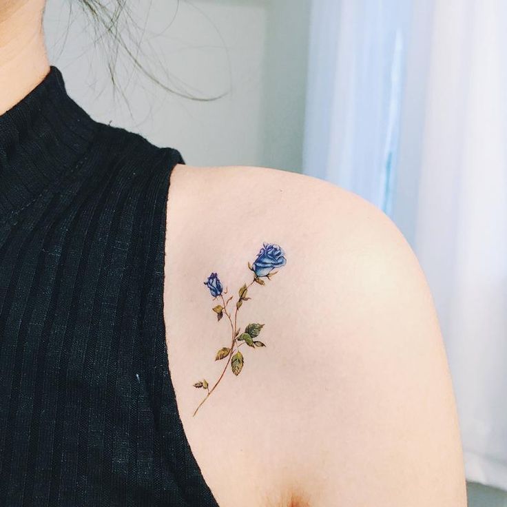 a blue rose tattoo on the back of a woman's shoulder