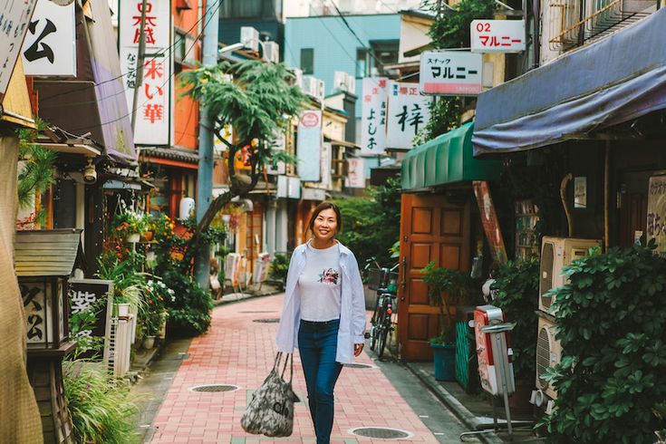 a woman is walking down an alley way carrying her purse and shopping bags in hand