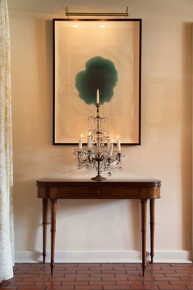 a table with a chandelier on top of it in front of a painting