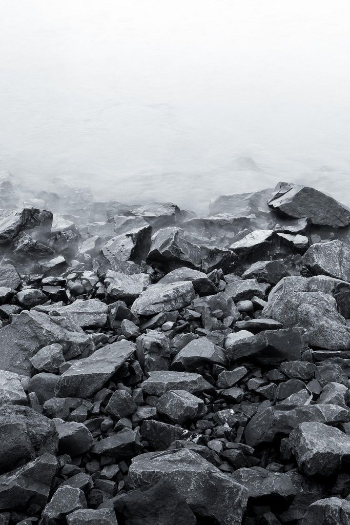 a black and white photo of rocks on the beach