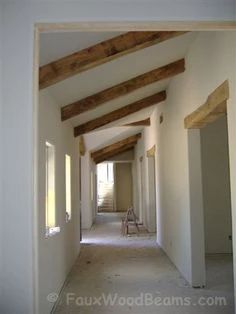 an empty hallway with white walls and wooden beams