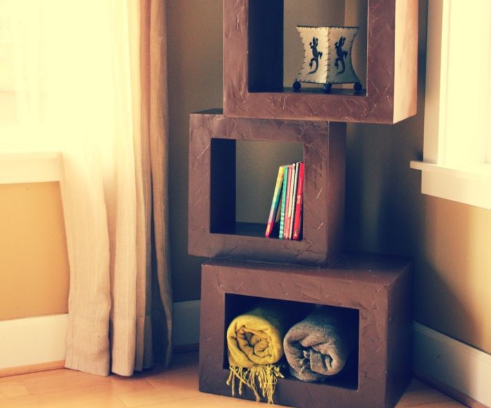 three shelves with books and blankets on them in front of a window, next to a pair of curtains