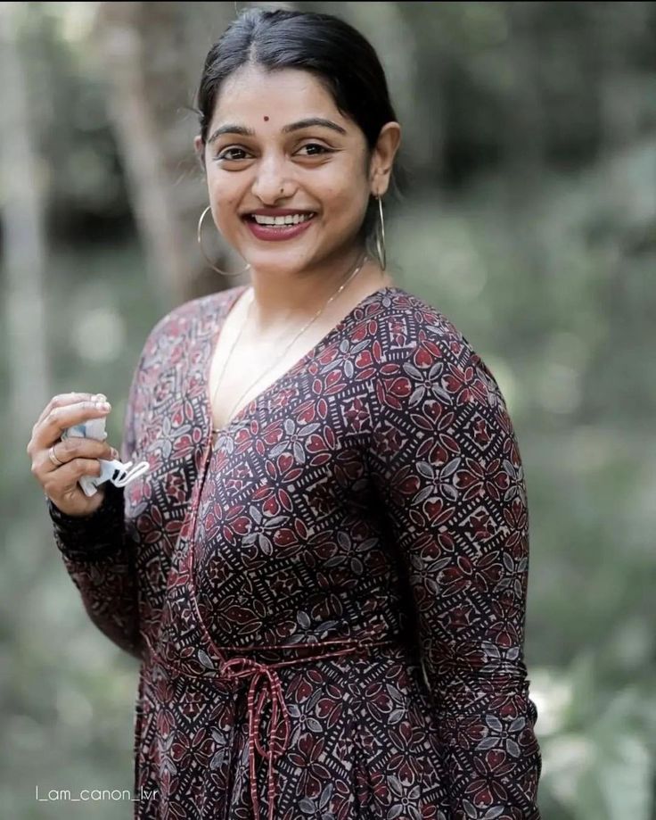 a woman in a red and black dress is holding a small object with her right hand