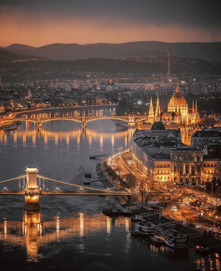 the city is lit up at night with lights on it and bridges across the river