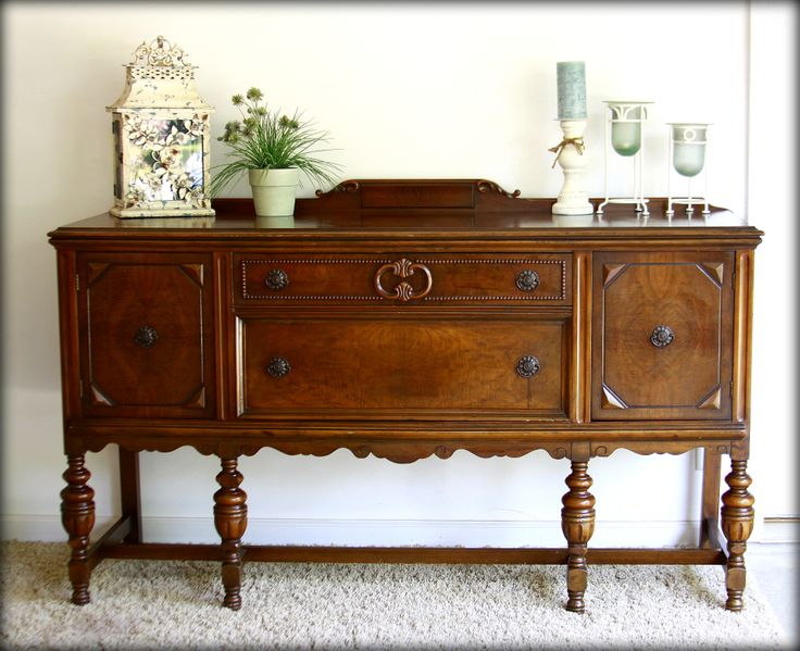 a wooden dresser with two vases on top of it next to a white wall