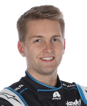 a man wearing a racing suit and smiling at the camera while standing in front of a white background