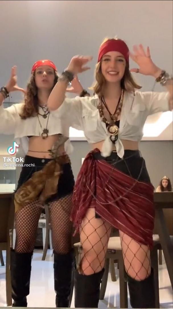 two women dressed in pirate garb posing for the camera with their hands up and legs crossed