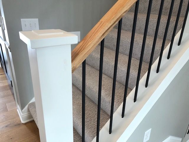 a stair case with black railing and wood handrail