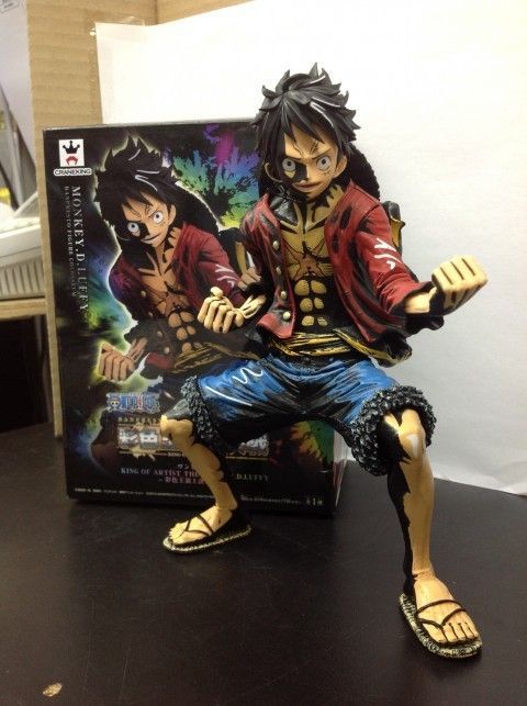 one piece action figure is posed next to a box with the same character on it