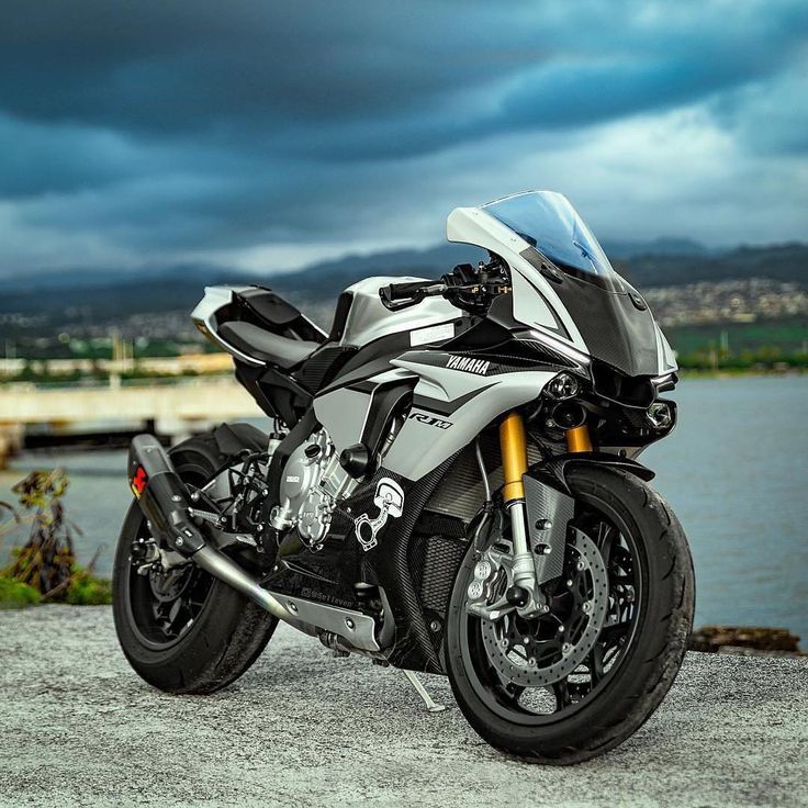 a silver motorcycle parked on the side of a road next to a body of water