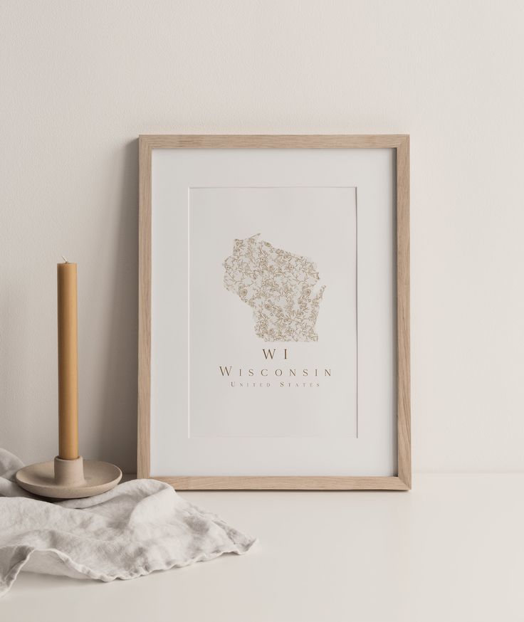 a white framed photograph sitting on top of a table next to a wooden candle holder