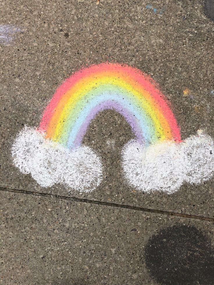 a rainbow painted on the sidewalk with white clouds