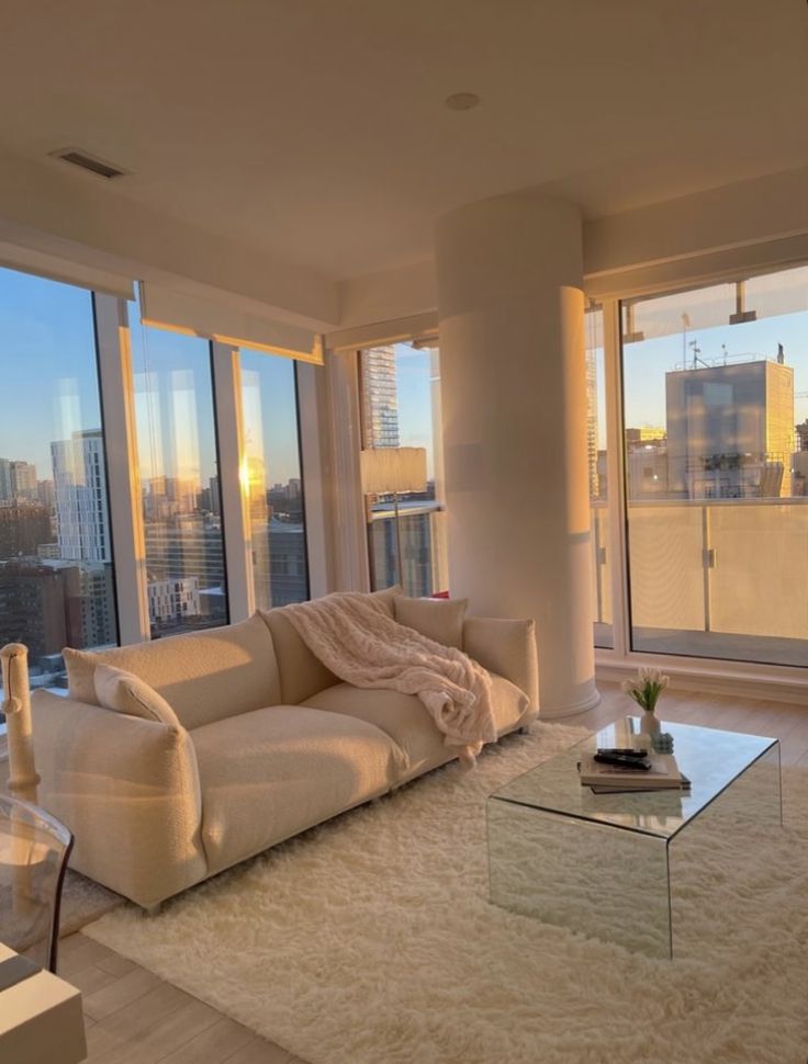 a living room filled with furniture and large windows overlooking the cityscape at sunset